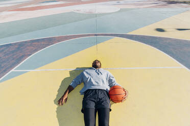 Tired basketball player lying on court - MEUF08192