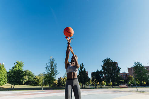 Basketballspieler wirft Ball an einem sonnigen Tag - MEUF08201