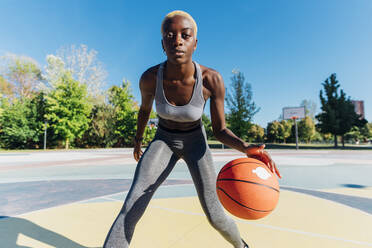 Selbstbewusste Sportlerin spielt Basketball auf dem Sportplatz - MEUF08203