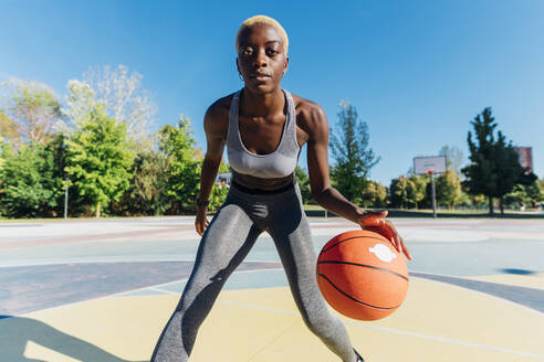 Selbstbewusste Sportlerin spielt Basketball auf dem Sportplatz - MEUF08203