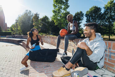 Basketballspieler beim Entspannen und Reden an einem sonnigen Tag - MEUF08207