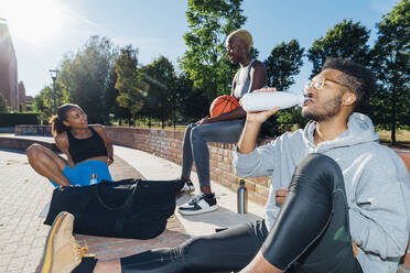Sportler trinkt Wasser bei Freunden an einem sonnigen Tag - MEUF08209