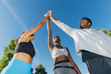 Smiling basketball players giving high-five on sunny day - MEUF08211