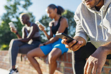 Sportler benutzt Mobiltelefon an einem sonnigen Tag - MEUF08234