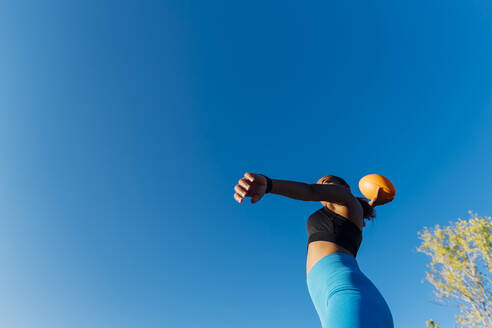 Junge Sportlerin wirft American Football an einem sonnigen Tag - MEUF08246