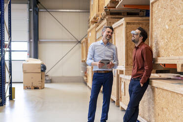 Businessman with colleague wearing virtual reality simulators at warehouse - JOSEF13796