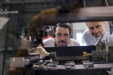 Mature businessman with colleague examining machinery at industry - JOSEF13804