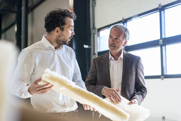 Senior businessman with colleague discussing over insulation at industry - JOSEF13845