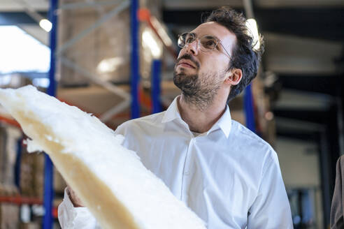 Businessman holding insulation at warehouse - JOSEF13846