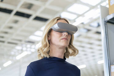 Businesswoman wearing virtual reality simulator at warehouse - JOSEF13858