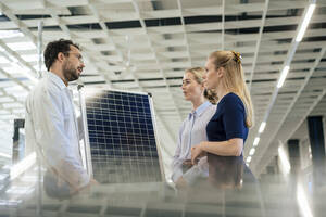Ingenieur, der ein Solarpanel hält und mit Kollegen in der Industrie diskutiert - JOSEF13900