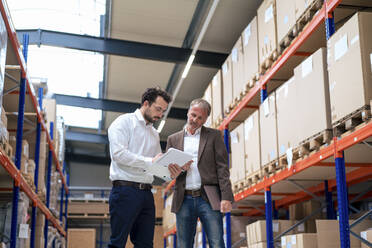 Businessman with colleague taking inventory at warehouse - JOSEF13923