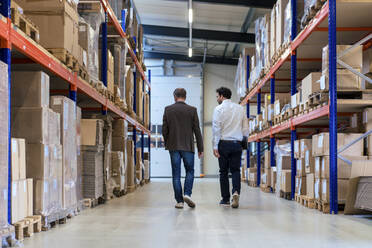 Businessman with colleague walking at warehouse - JOSEF13939