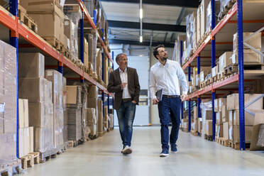 Businessman walking with colleague at warehouse - JOSEF13941