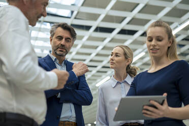 Smiling young businesswoman with tablet PC discussing with colleagues - JOSEF13953