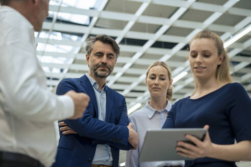 Businesswoman explaining colleagues over digital tablet in industry - JOSEF13954