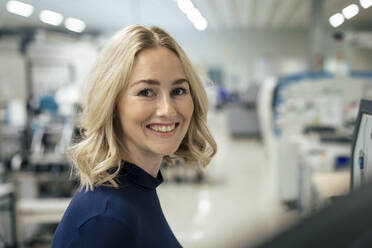 Happy businesswoman with blond hair at industry - JOSEF13971