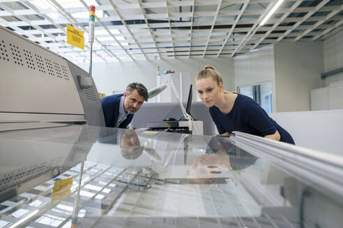 Junge Geschäftsfrau mit Geschäftsmann bei der Untersuchung einer 3D-Druckmaschine - JOSEF14047