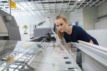 Young businesswoman examining 3D printing machine in industry - JOSEF14048