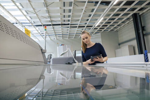 Junge Geschäftsfrau mit Tablet-PC, die eine 3D-Druckmaschine in der Industrie untersucht - JOSEF14049