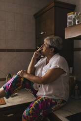Frau raucht Zigarette in der Küche - EGHF00566
