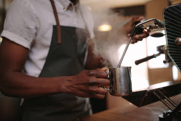 Kaffeehausbesitzer bereitet Kaffee auf einer Dampf-Espressomaschine zu. Ausschnitt eines Mannes, der in seinem Kaffeehaus arbeitet und eine Schürze trägt. - JLPSF04942