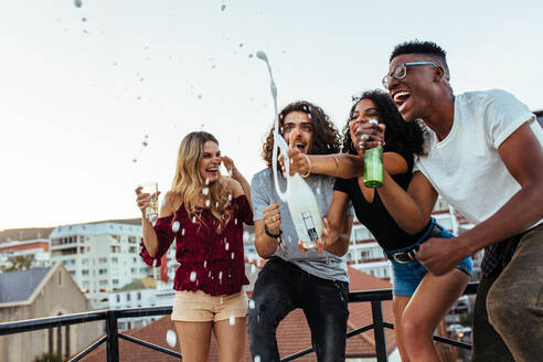 Diverse group of friends celebrating party with champagne. Men and women having a great time at the rooftop party. - JLPSF05017