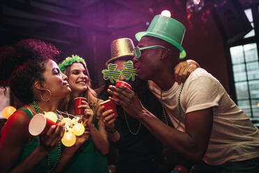 Multi-ethnische Männer und Frauen amüsieren sich an der Bar. Eine Gruppe von Freunden feiert den St. Patrick's Day in einem Nachtclub. - JLPSF05019