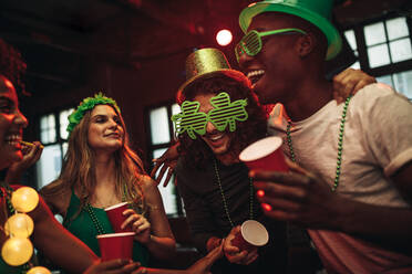 Eine Gruppe junger Männer und Frauen feiert den St. Patrick's Day, Freunde haben Spaß an der Bar mit grünen Partygläsern und Hut. - JLPSF05020