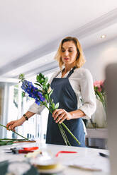 Woman florist making bouquet at flower shop. Female working at flower shop arranging flowers. - JLPSF05042