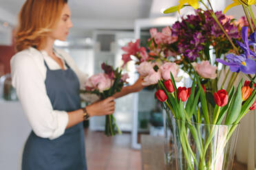 Kleines Geschäft. Floristin unkonzentriert in Blumenladen. Floral Design Studio mit Blumen in Vase angeordnet. - JLPSF05048