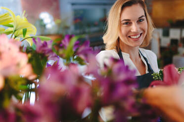 Smiling florist working in her shop. Beautiful caucasian woman in flower shop. - JLPSF05061