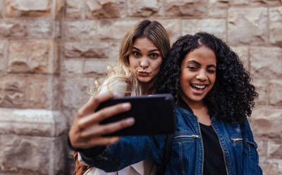 Glückliche Mädchen, die ein Selfie mit dem Handy machen. Frauen machen Gesichter beim Posieren für ein Selfie. - JLPSF05096