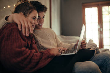 Mann und Frau sitzen auf der Couch und schauen auf einen Laptop-Computer. Paar benutzt Laptop im Wohnzimmer. - JLPSF05107