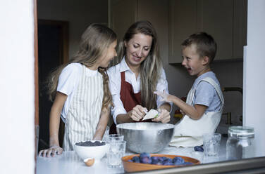 Fröhliche Kinder helfen der Mutter beim Kochen zu Hause - NJAF00044