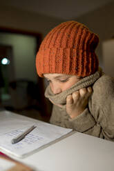 Boy wearing knit hat studying at home - ANAF00156