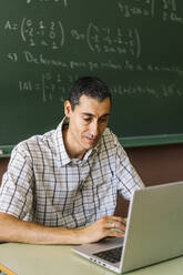 Mathematiklehrer benutzt Laptop im Klassenzimmer - DAMF01094