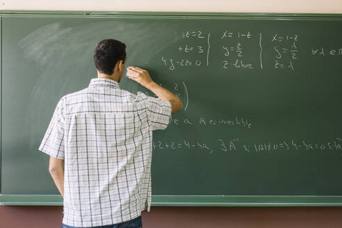Teacher erasing math formulas on chalkboard - DAMF01100