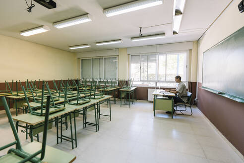 Mathelehrer sitzt im leeren Klassenzimmer - DAMF01102