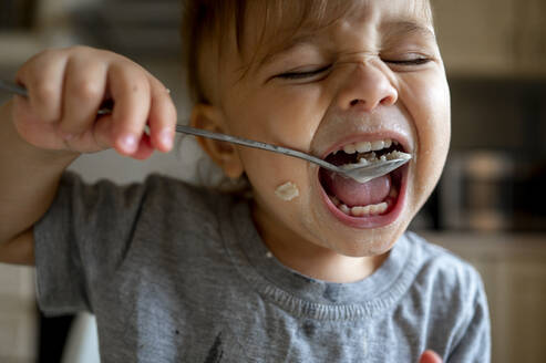 Baby boy eating porridge with spoon - ANAF00164