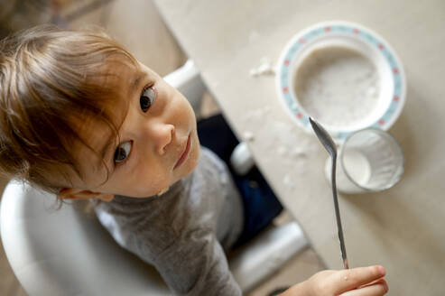 Babyjunge mit Löffel beim Frühstück am Tisch - ANAF00165