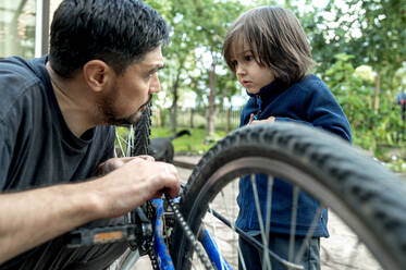 Vater unterrichtet Sohn bei der Reparatur eines Fahrrads - ANAF00170