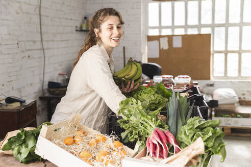 Happy owner picking up vegetables in greengrocer shop - PCLF00138