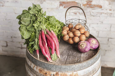 Fresh vegetables with eggs in basket on barrel - PCLF00160