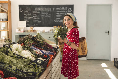 Senior customer buying vegetables in greengrocer shop - PCLF00163