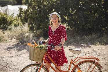 Lächelnde ältere Frau mit Gemüse im Fahrradkorb - PCLF00168