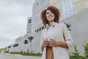 Contemplative young businesswoman standing outside building - YTF00223