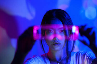 Young woman looking through LED futuristic glasses - JSMF02448