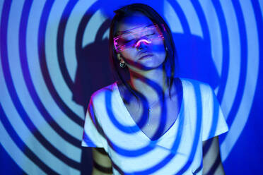 Spiral shadow on young woman wearing LED smart glasses - JSMF02449