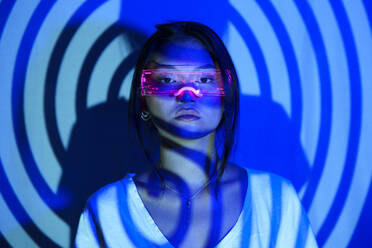 Spiral shadow on young woman wearing LED futuristic glasses - JSMF02450